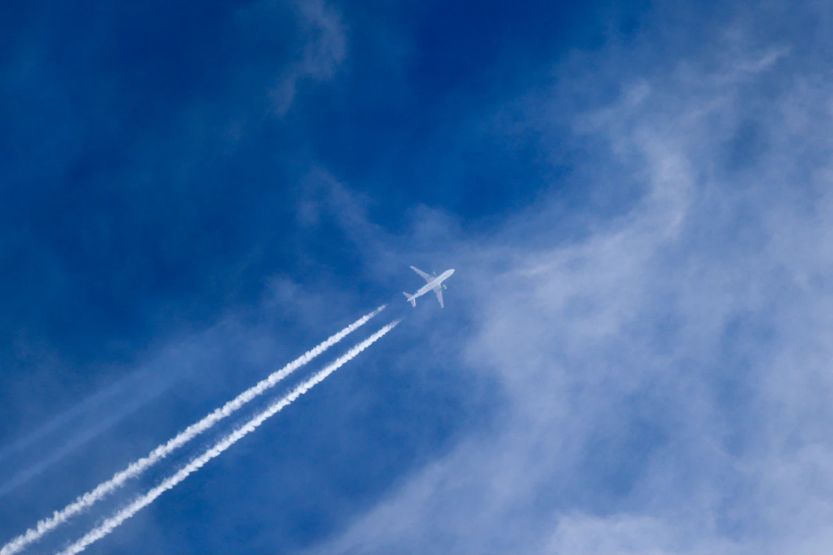 Aircraft climbing into a clear sky leaving a long contrail