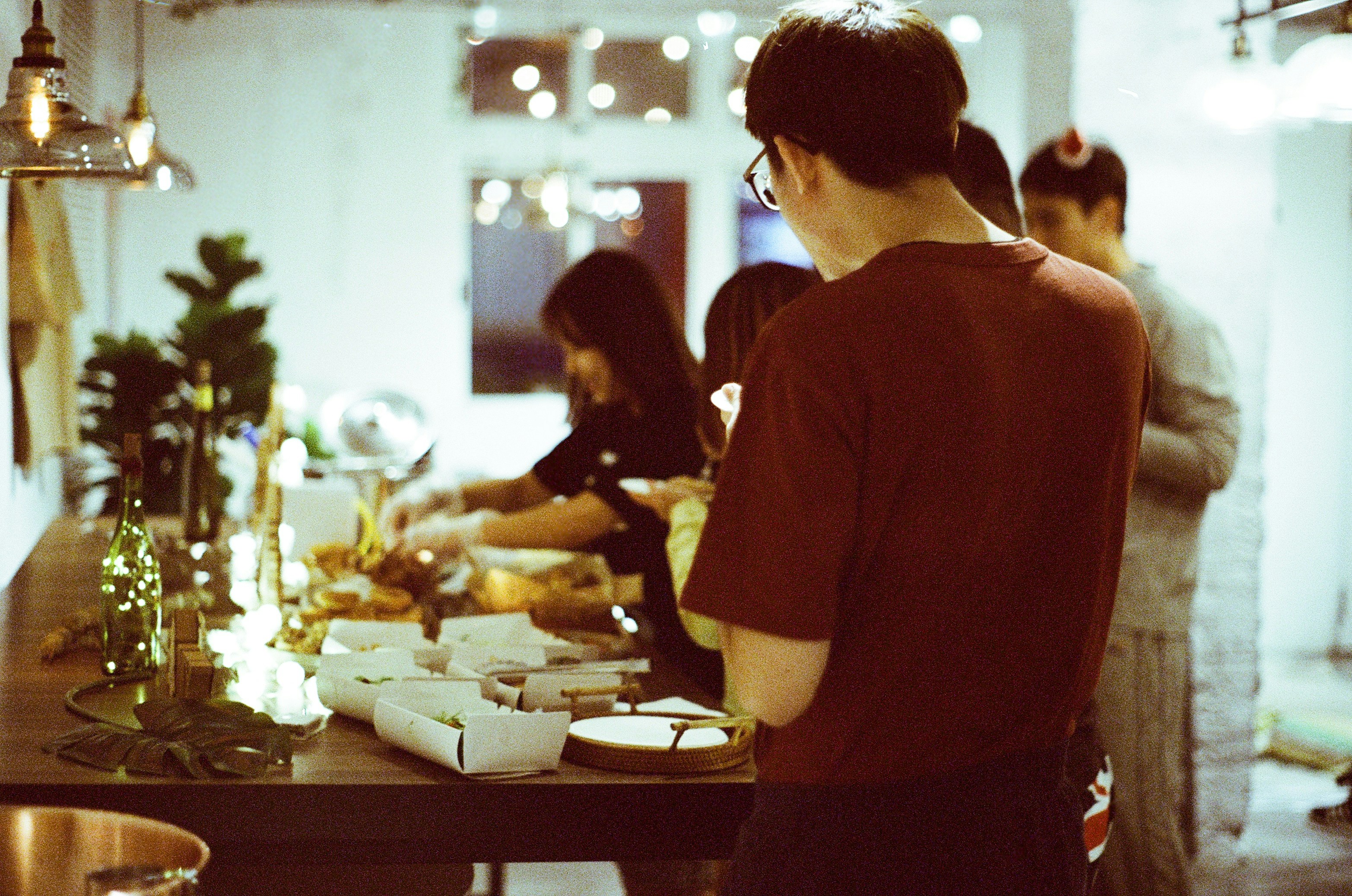 a group of people standing around a table with food on it