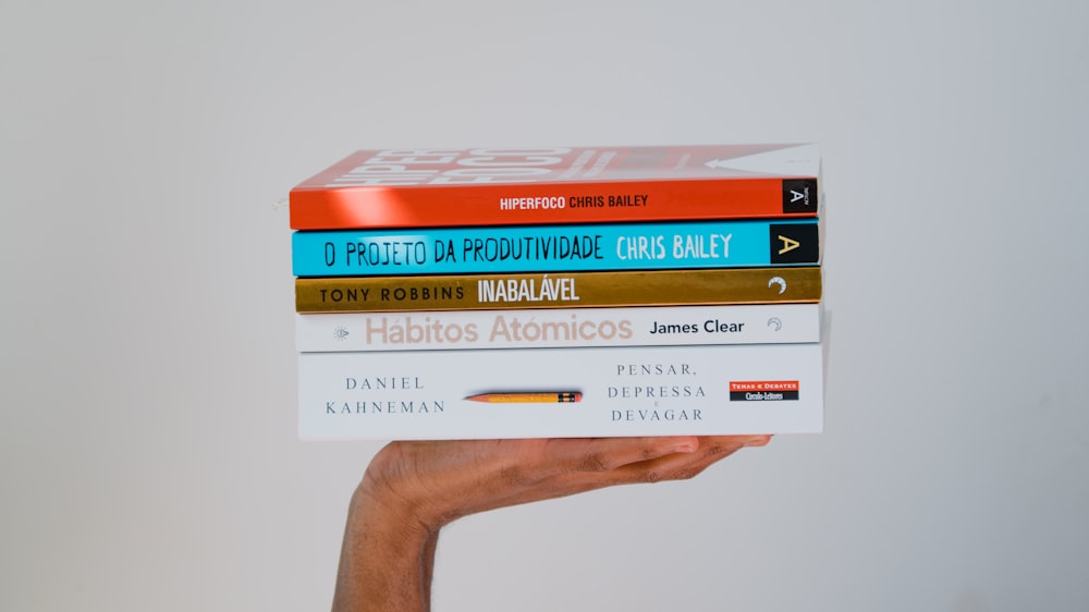 a hand holding a stack of five books