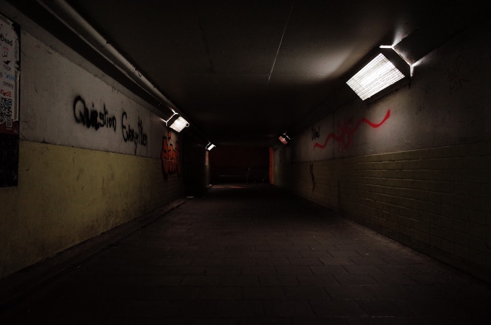 a dark hallway with graffiti on the walls