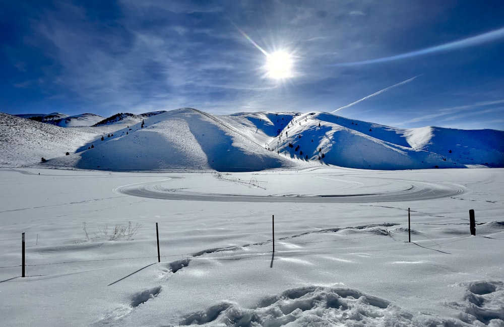 a snow covered field with mountains in the background