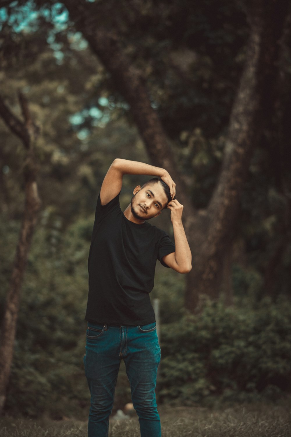 a man standing in a forest with his hands on his head