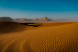 a desert landscape with sand dunes and mountains in the background