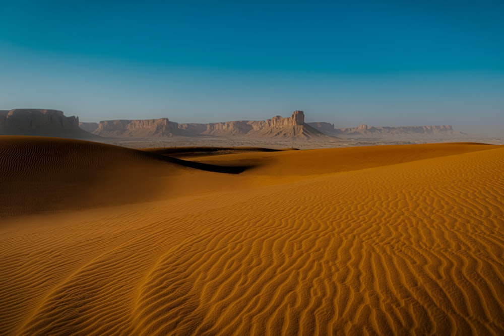 a desert landscape with sand dunes and mountains in the background