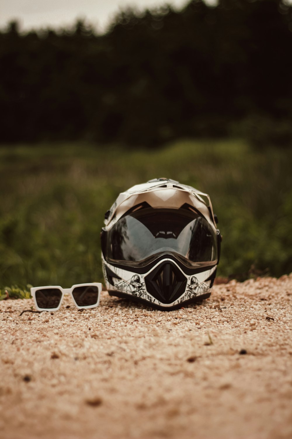 a helmet and sunglasses sitting on a dirt road