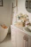 A serene bathroom setting featuring elegant bath products arranged on a wooden shelf with soft lighting.