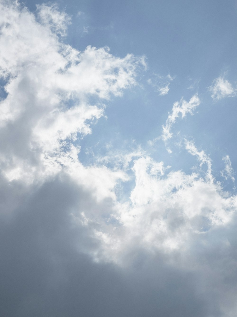 a plane flying through a cloudy blue sky