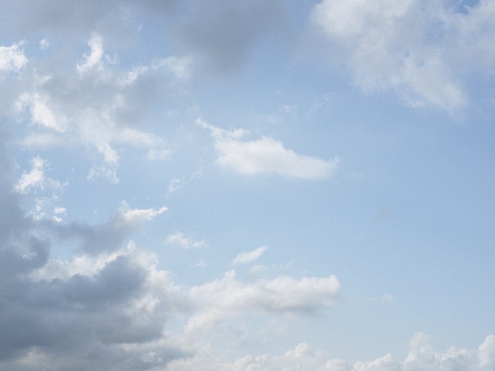 a plane flying in a cloudy blue sky