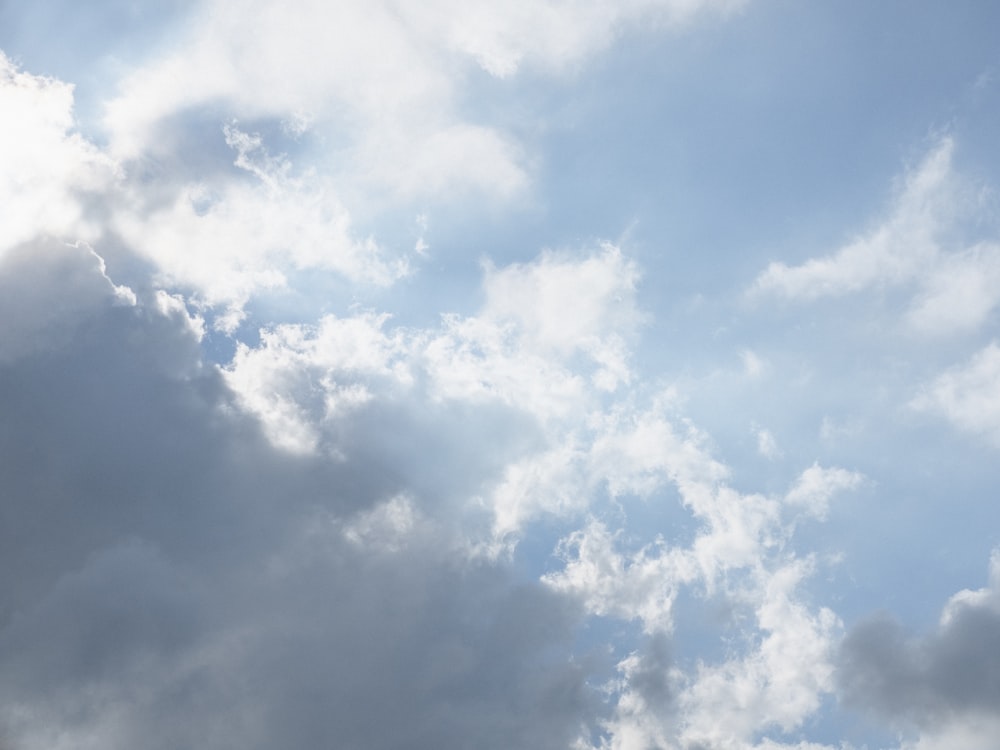 a plane flying through a cloudy blue sky