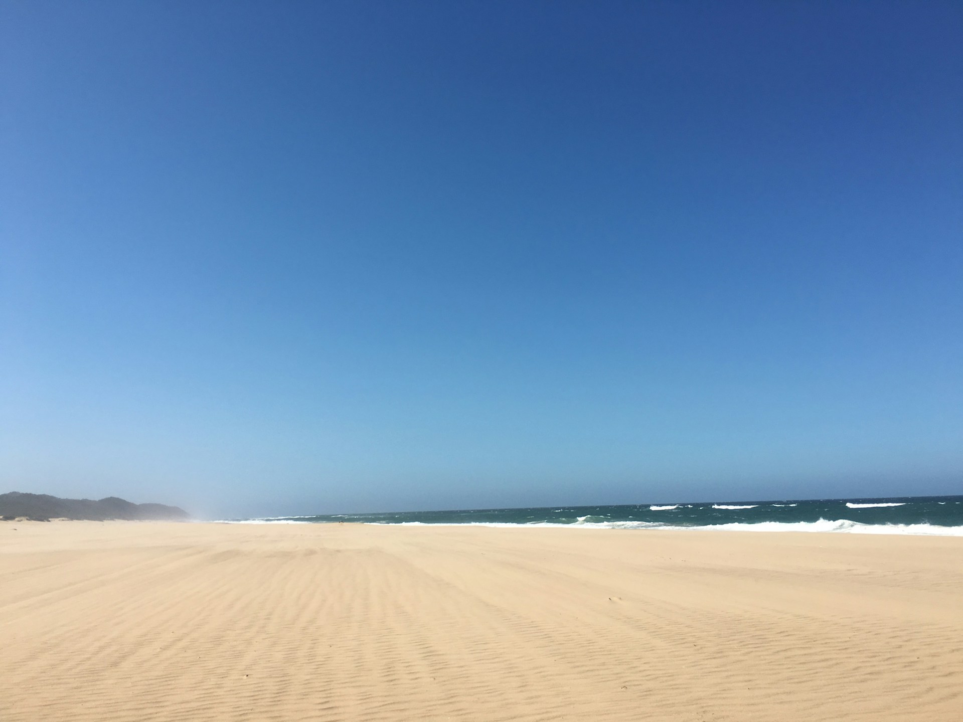 a sandy beach with waves coming in from the ocean
