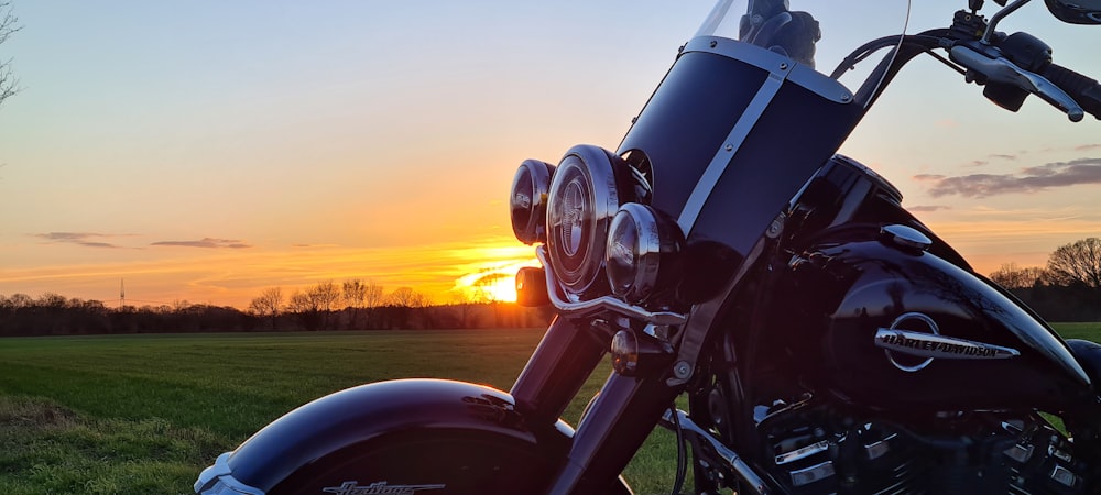a motorcycle parked in a field at sunset