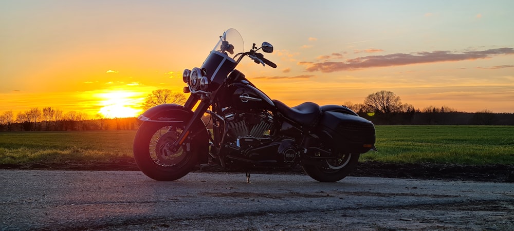 a motorcycle parked on the side of a road at sunset