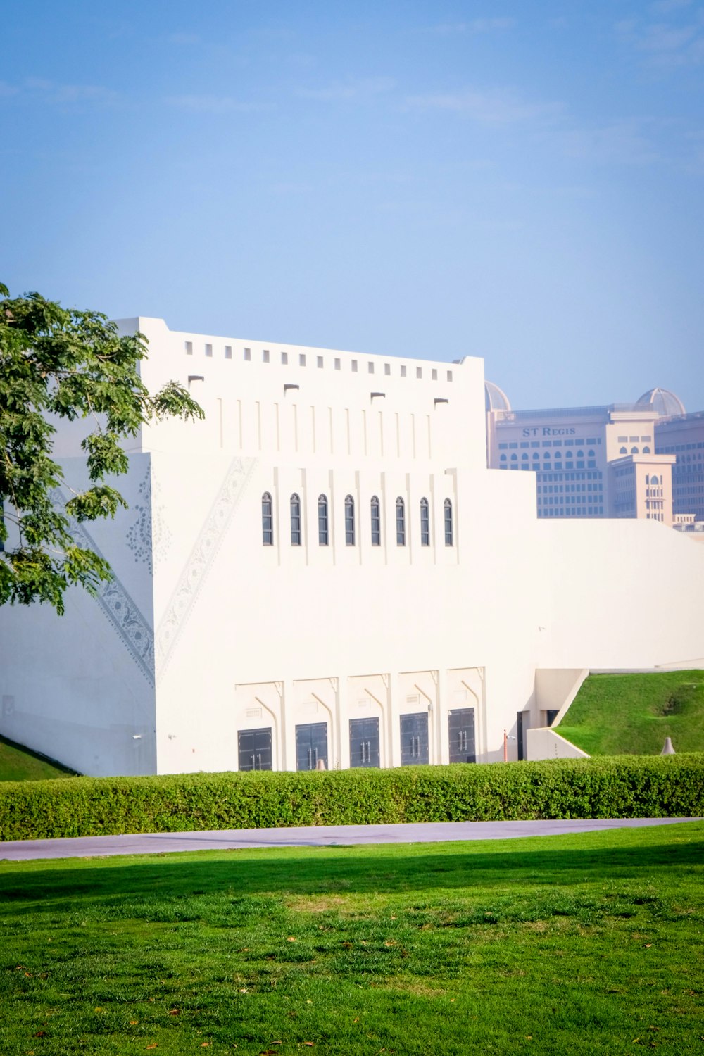 a large white building sitting on top of a lush green field