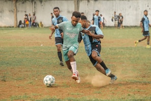A spirited match moment with a player skillfully dribbling past opponents on a lush green field.