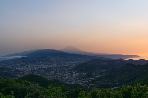 a view of a city and mountains at sunset
