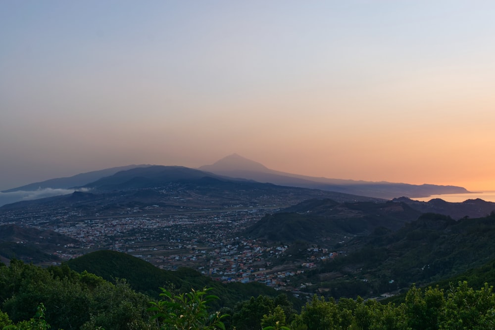 a view of a city and mountains at sunset