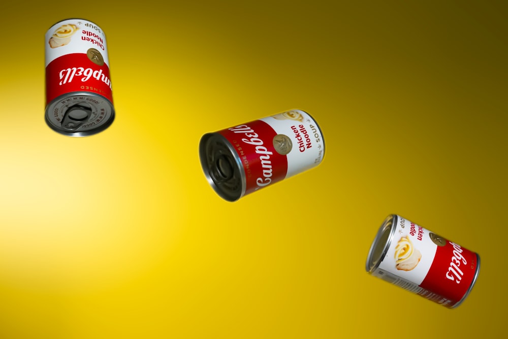 a group of three cans of soda on a yellow background
