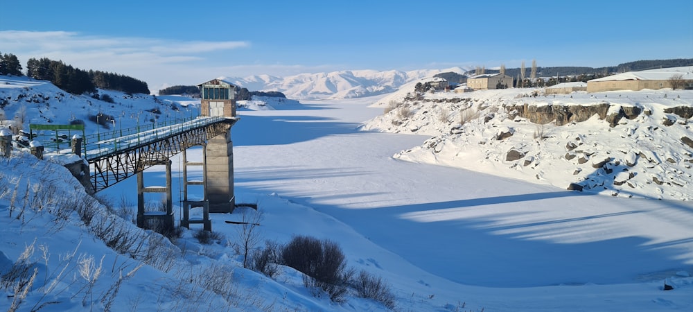 a bridge over a frozen river surrounded by mountains