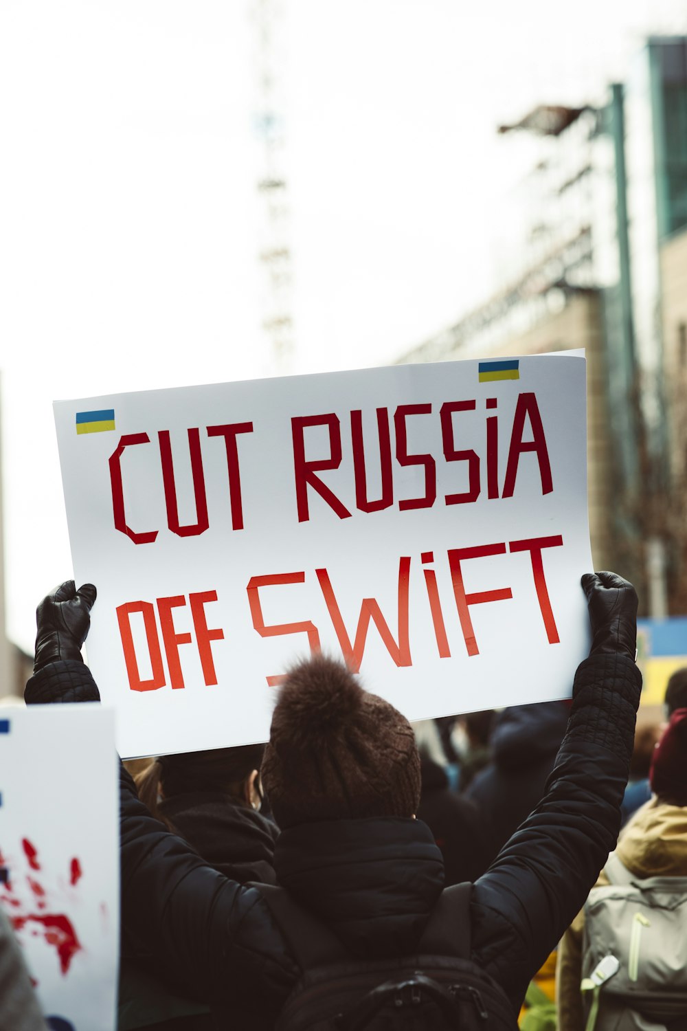 a person holding a sign that says cut russia off swift