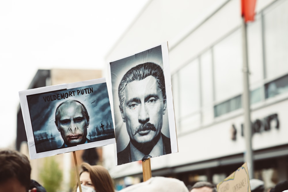 a group of people holding signs with pictures of men