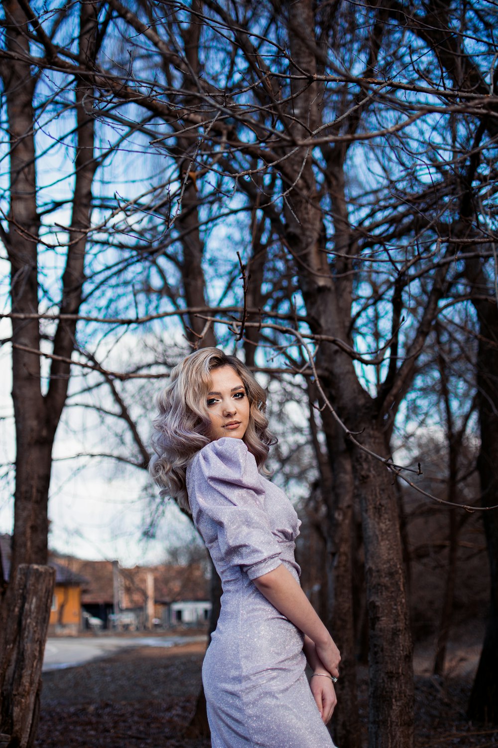 a woman in a dress standing in front of trees