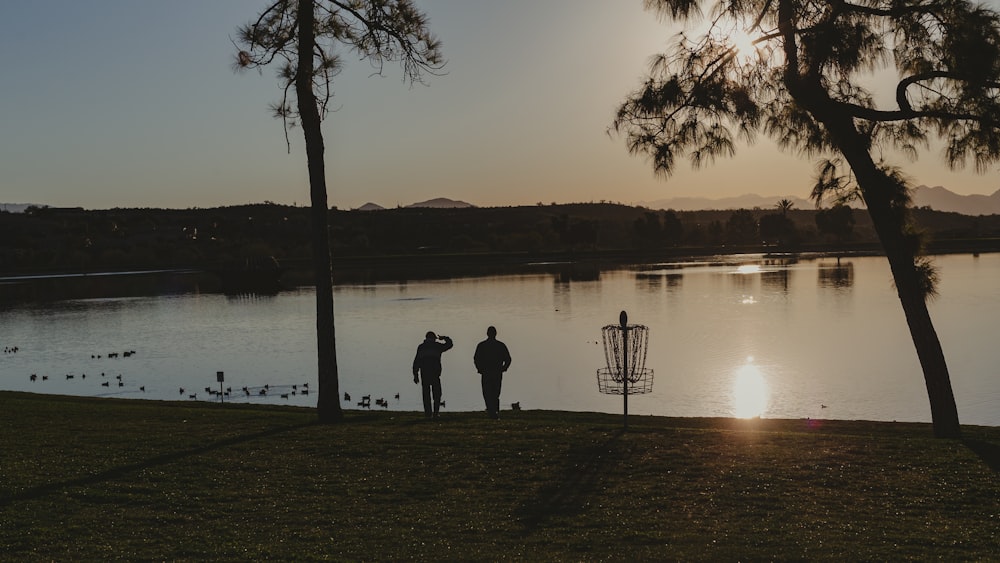 a couple of people standing next to a lake