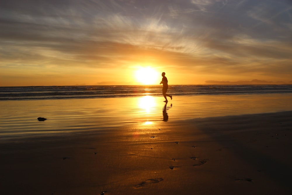 a person walking on a beach at sunset