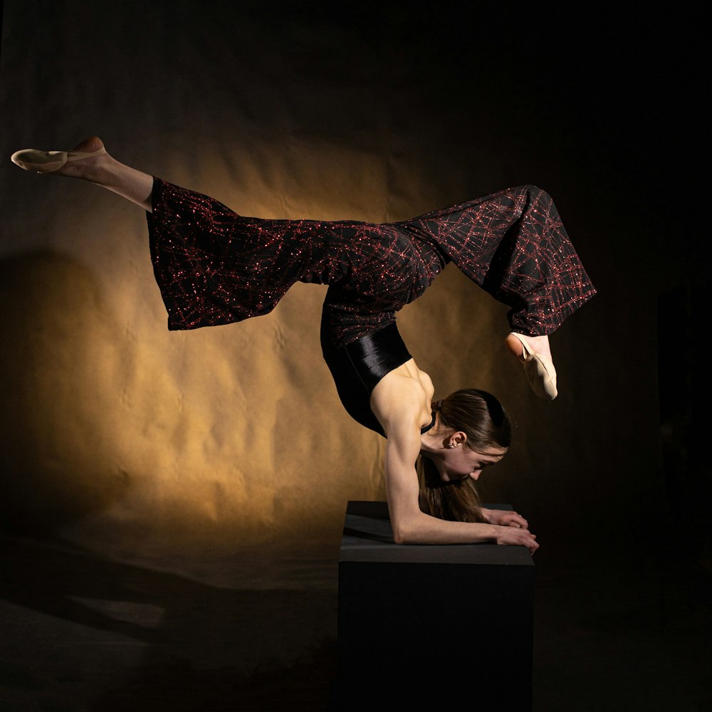 a woman doing a handstand on top of a box