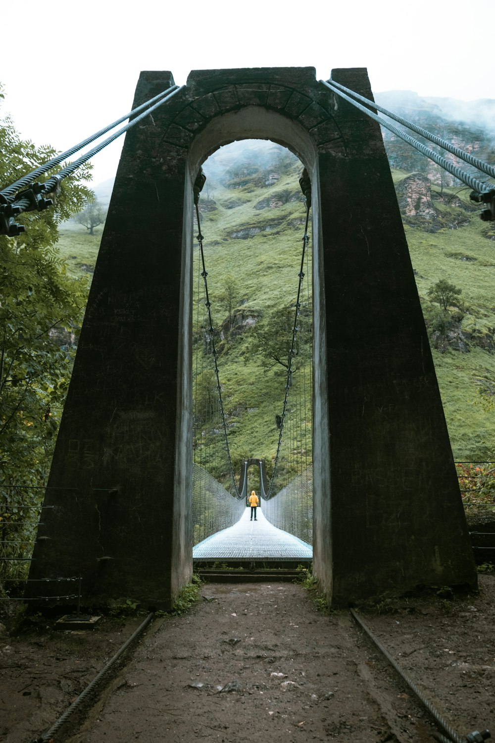 a man walking across a suspension bridge over a river