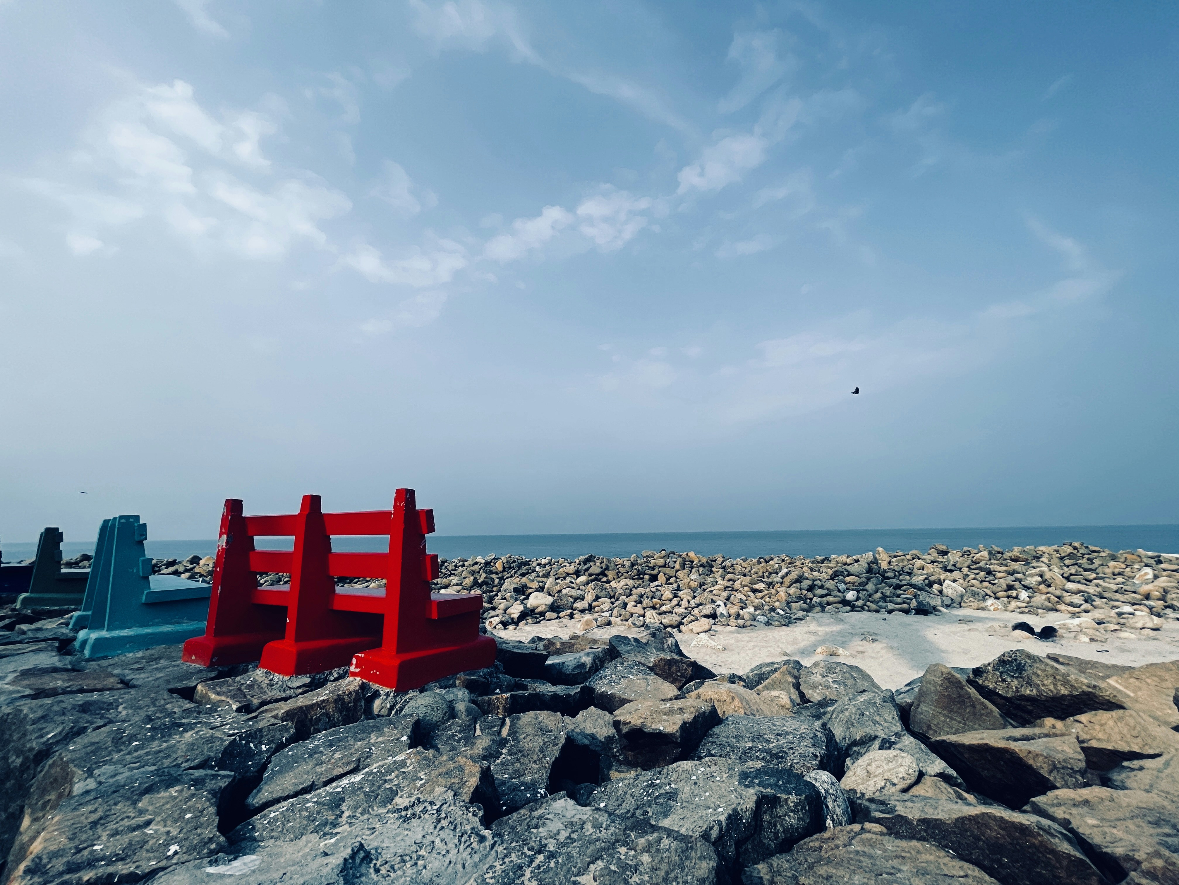 a couple of red chairs sitting on top of a rocky beach