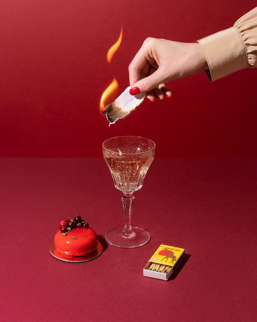 a person is holding a lighter over a small red cake