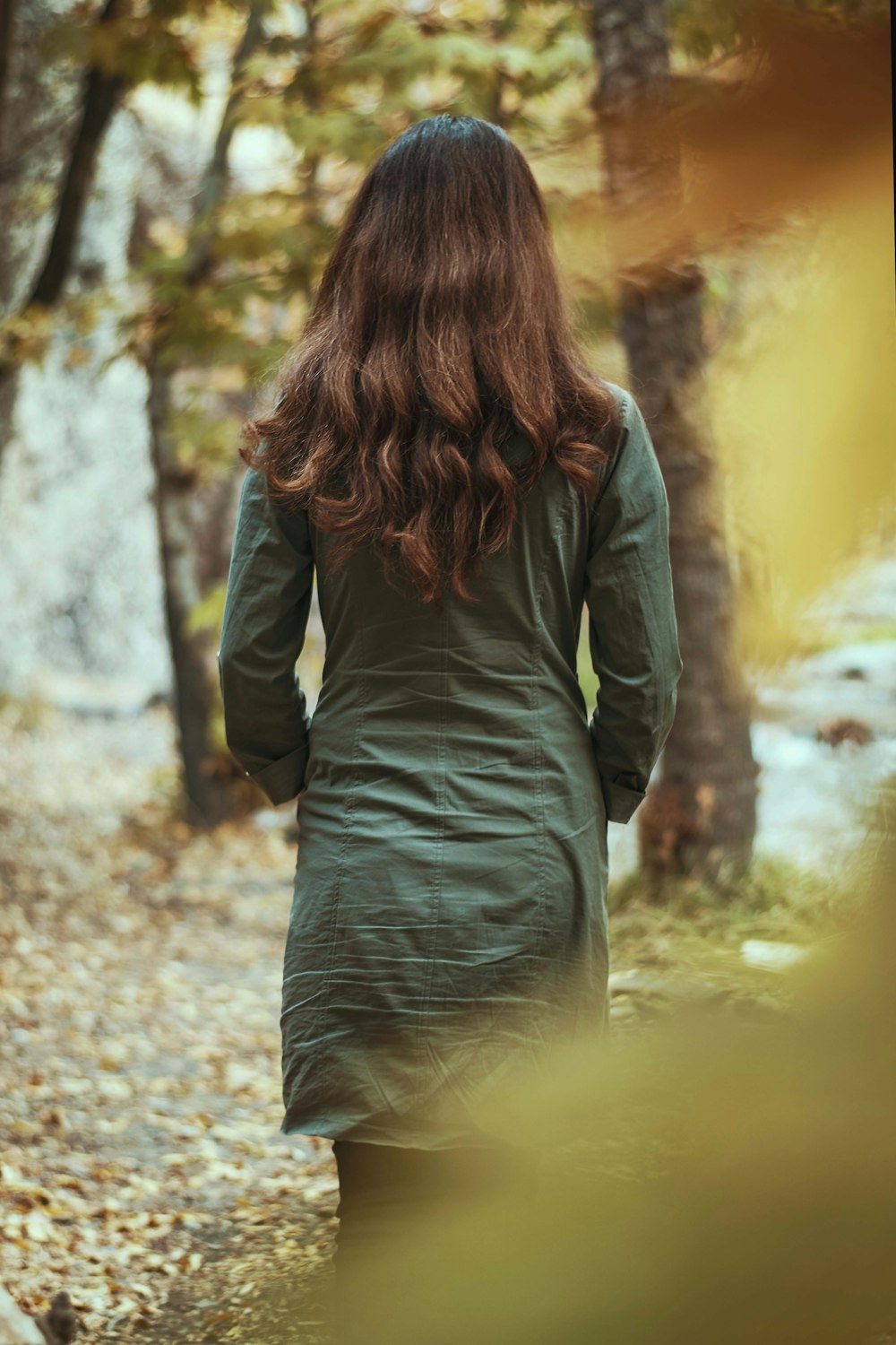 a woman in a green dress walking through a forest