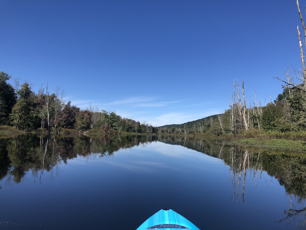 a blue kayak on a calm lake surrounded by trees