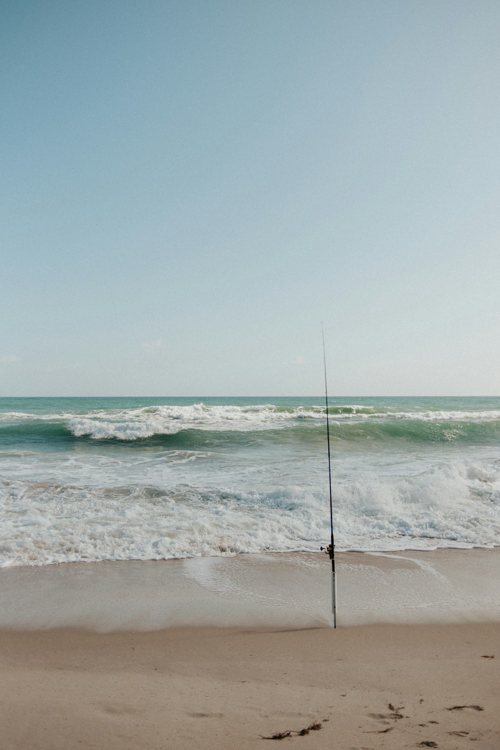a fishing pole sticking out of the sand of a beach