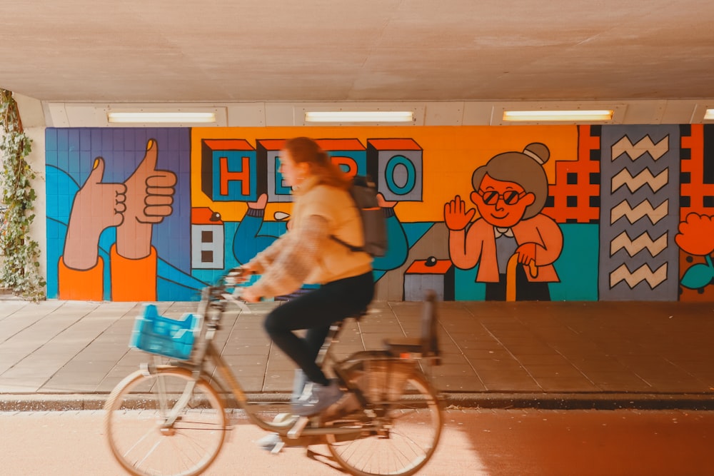 a woman riding a bike in front of a colorful wall