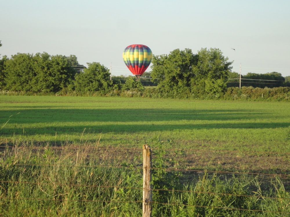a hot air balloon flying over a lush green field