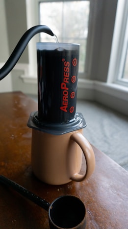 An Aeropress in action, with coffee being pressed into a mug on a kitchen counter.