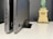 Two laptops in a vertical standing position are placed on a desk against a neutral background. In the foreground, the edges and ports of the laptops are visible, suggesting a focus on design and technology. In the background, there is a small model resembling the Statue of Liberty, contributing an element of decor or personal touch to the workspace.