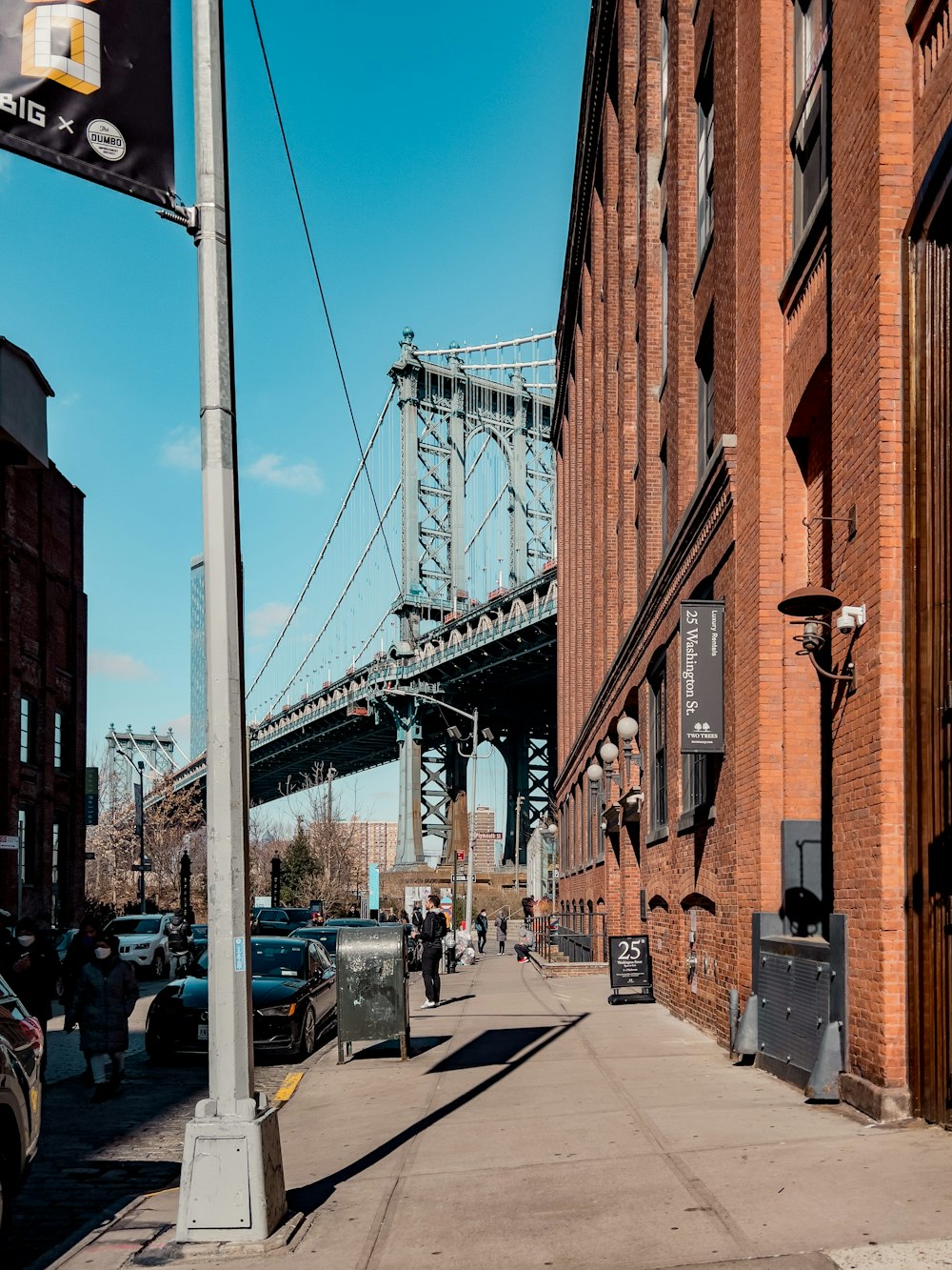 a street with cars parked on the side of it and a bridge in the background