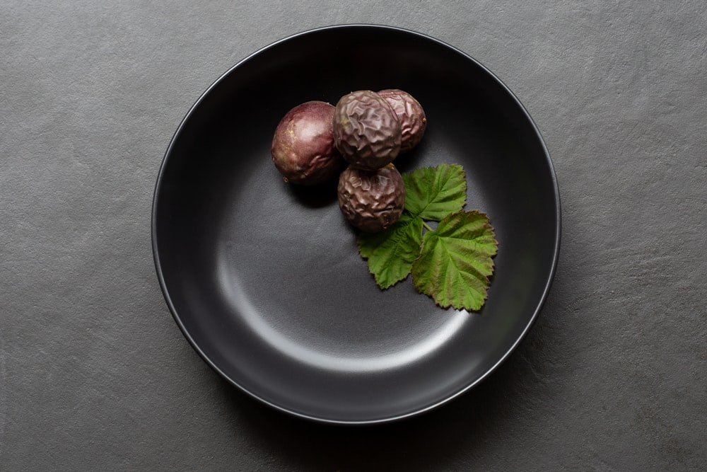 a black plate topped with three figs and a leaf