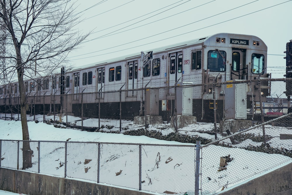 a train traveling down tracks next to a snow covered field