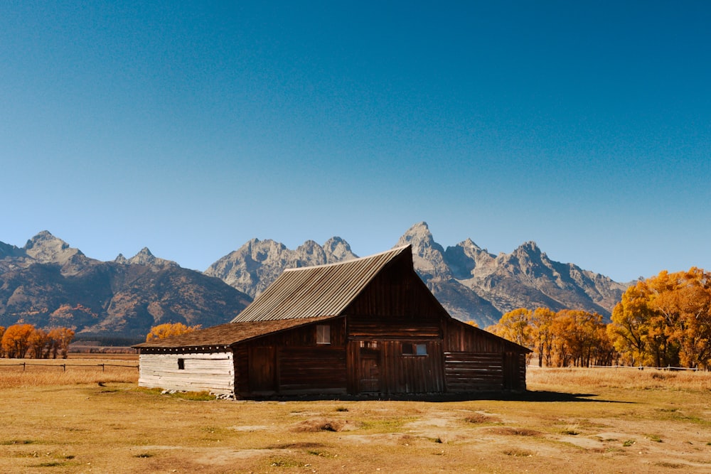 a barn in a field with mountains in the background