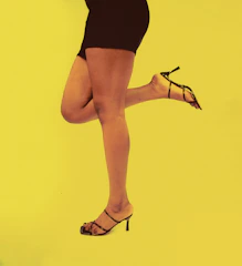 A model smiling confidently while showcasing her feet in stylish heels.