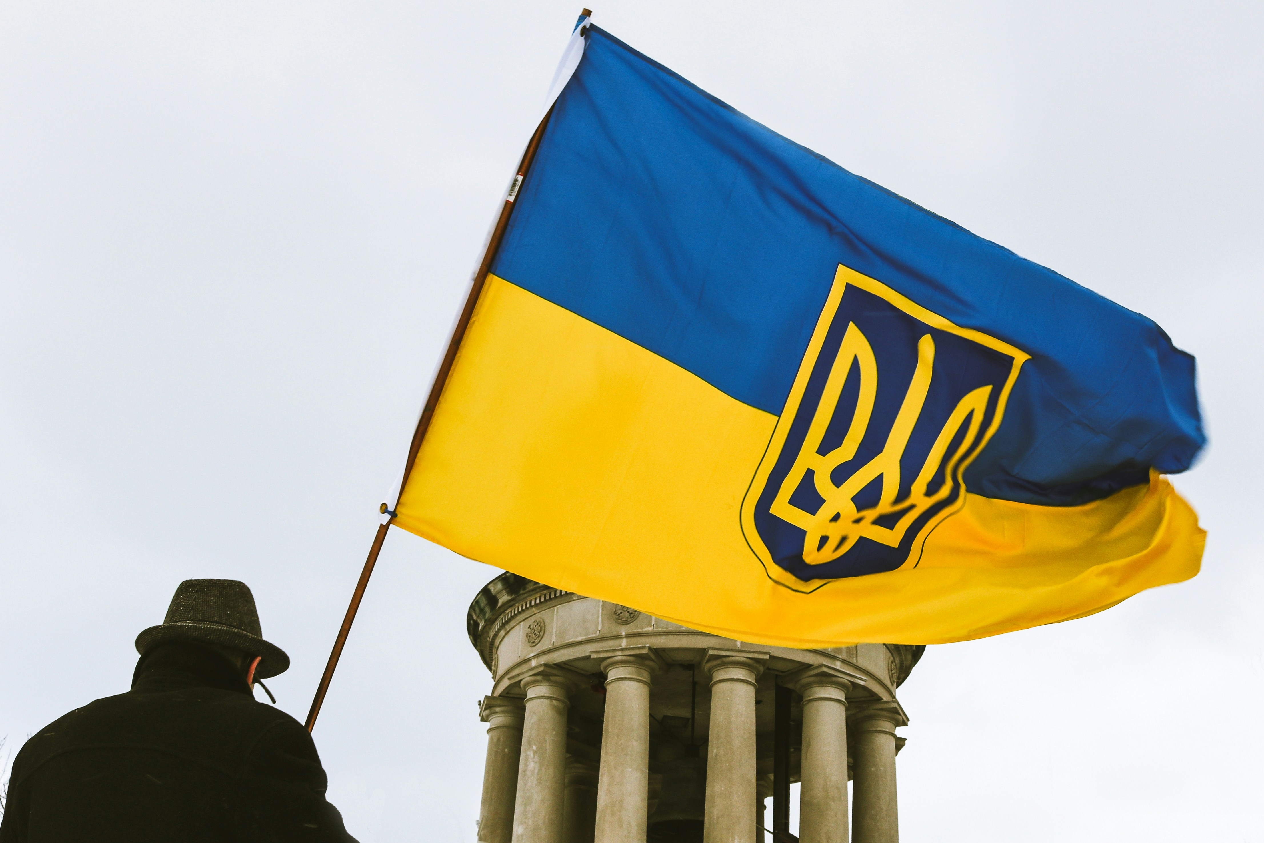 A man waving the Ukrainian flag with the Coat of arms of Ukraine insignia.
