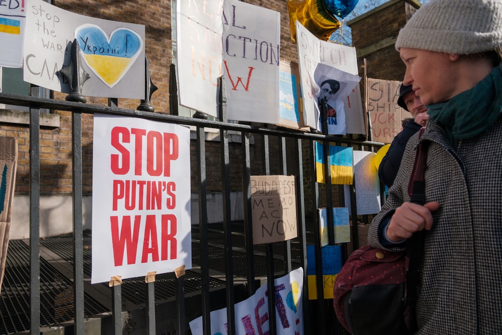 a woman standing in front of a fence with signs on it