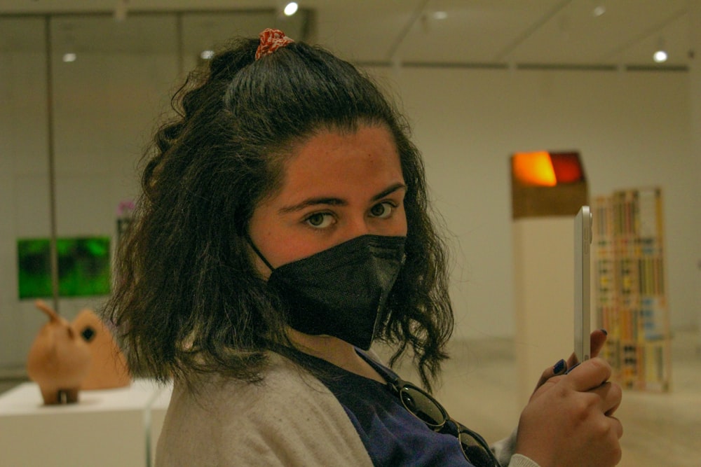 a woman wearing a face mask holding a cell phone