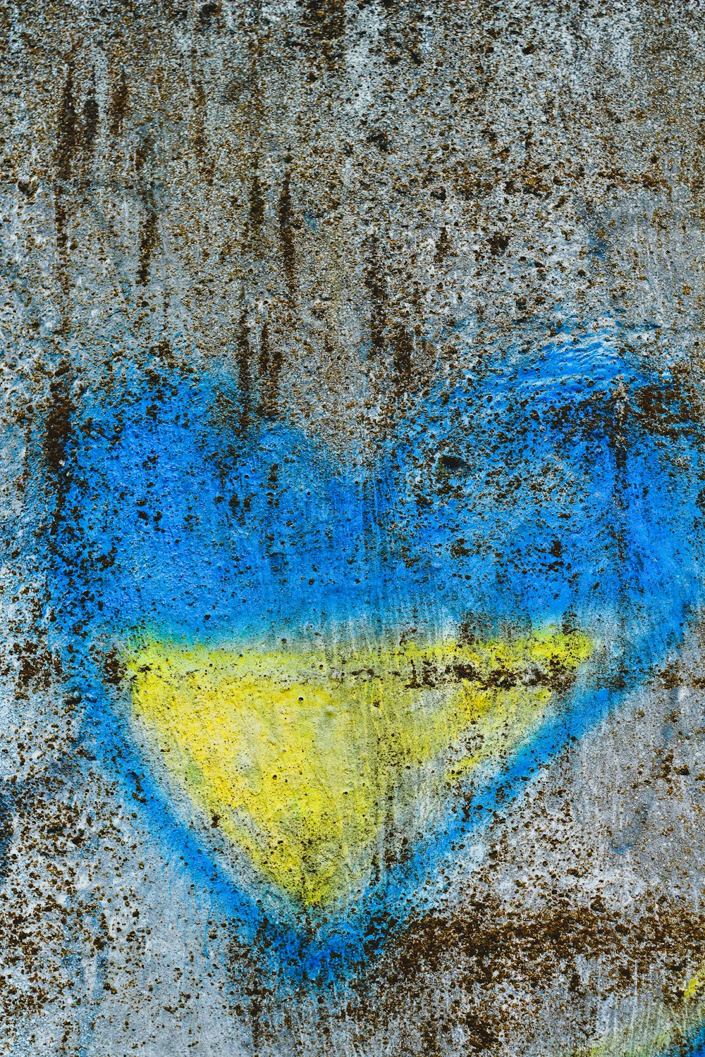 a heart painted on a wall with blue and yellow paint