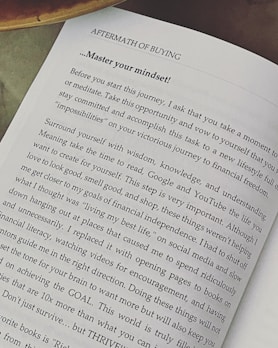 A page from a book titled 'Aftermath of Buying' focuses on mastering one's mindset. The text advises taking time to meditate, surround yourself with wisdom and understanding, and avoid distractions. It emphasizes setting goals and thriving instead of just surviving.