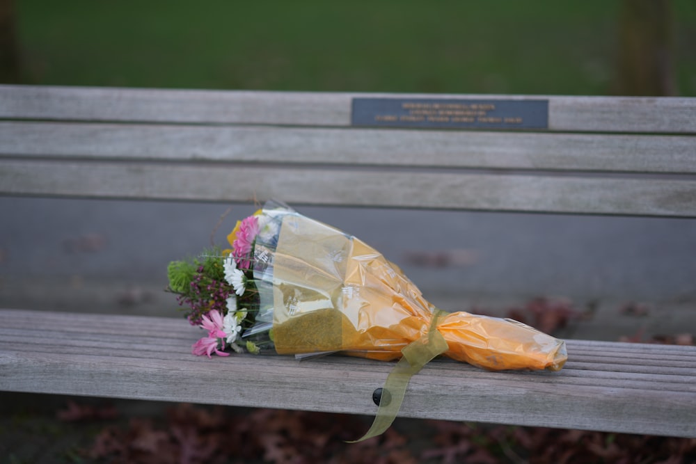 a bouquet of flowers sits on a park bench