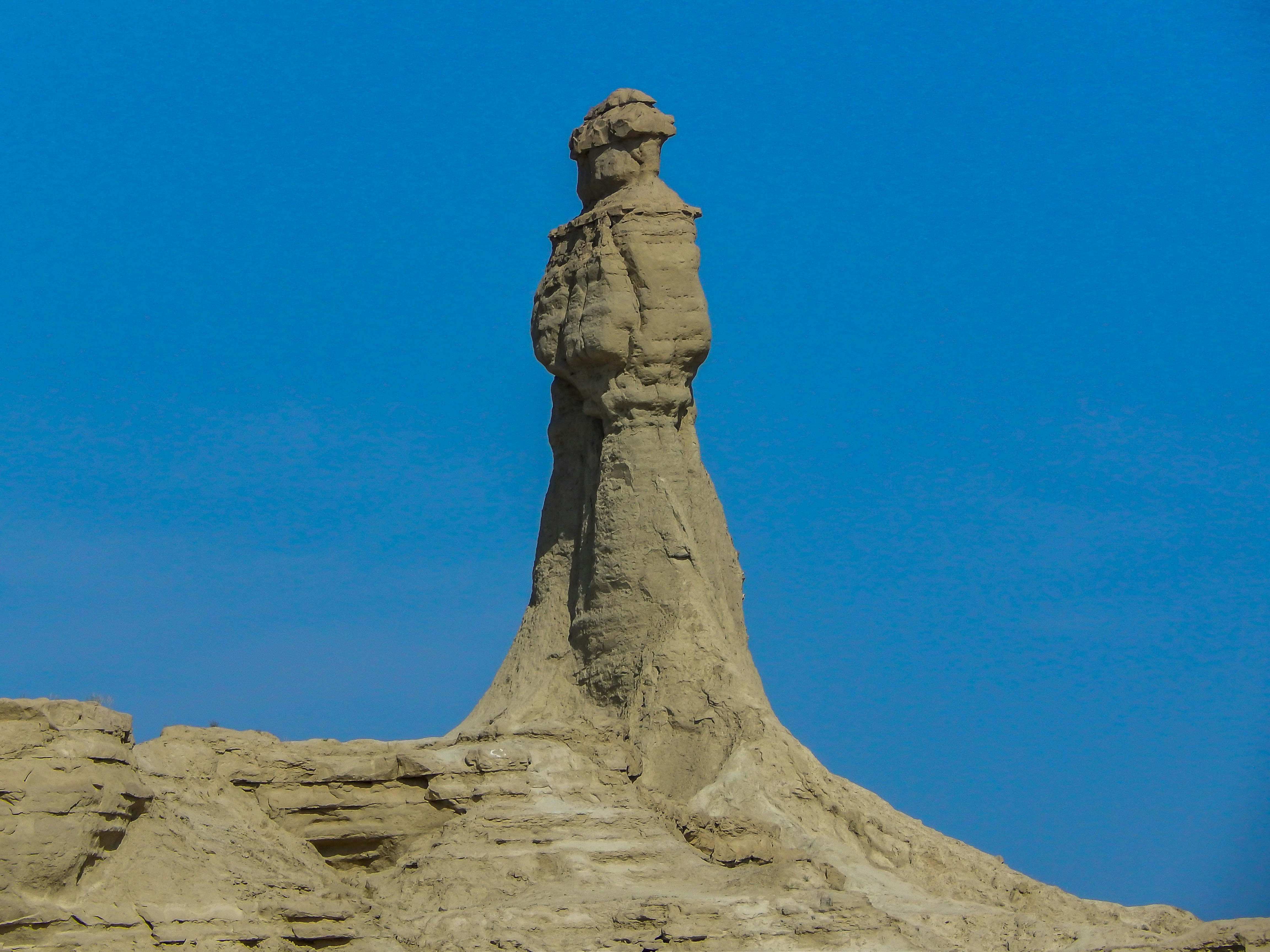Una gran escultura de arena de una persona en la cima de una colina